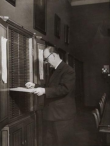 Mann an einem Münzschrank, eine Lade herausgezogen, Schwarz-Weiß-Foto