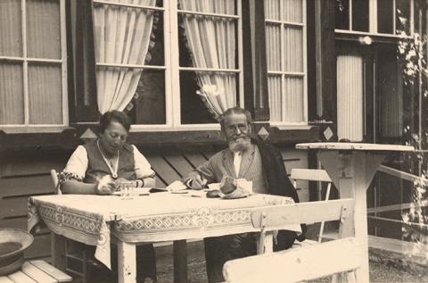 Ehepaar sitzt an einem Tisch vor einem Haus, Schwarz-Weiß-Foto