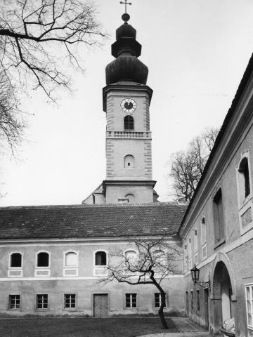 Schwarzweißfoto mit Kirchturm und Wohngebäude