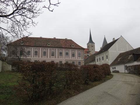 Blick hangaufwärts auf ein großes Gebäude sowie weitere Häuser und einen Kirchturm, Farbfoto