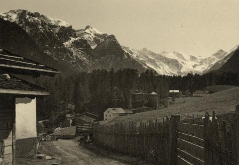 Blick in ein Gebirgstal mit verschiedenen Gebäuden, Schwarz-Weiß-Foto